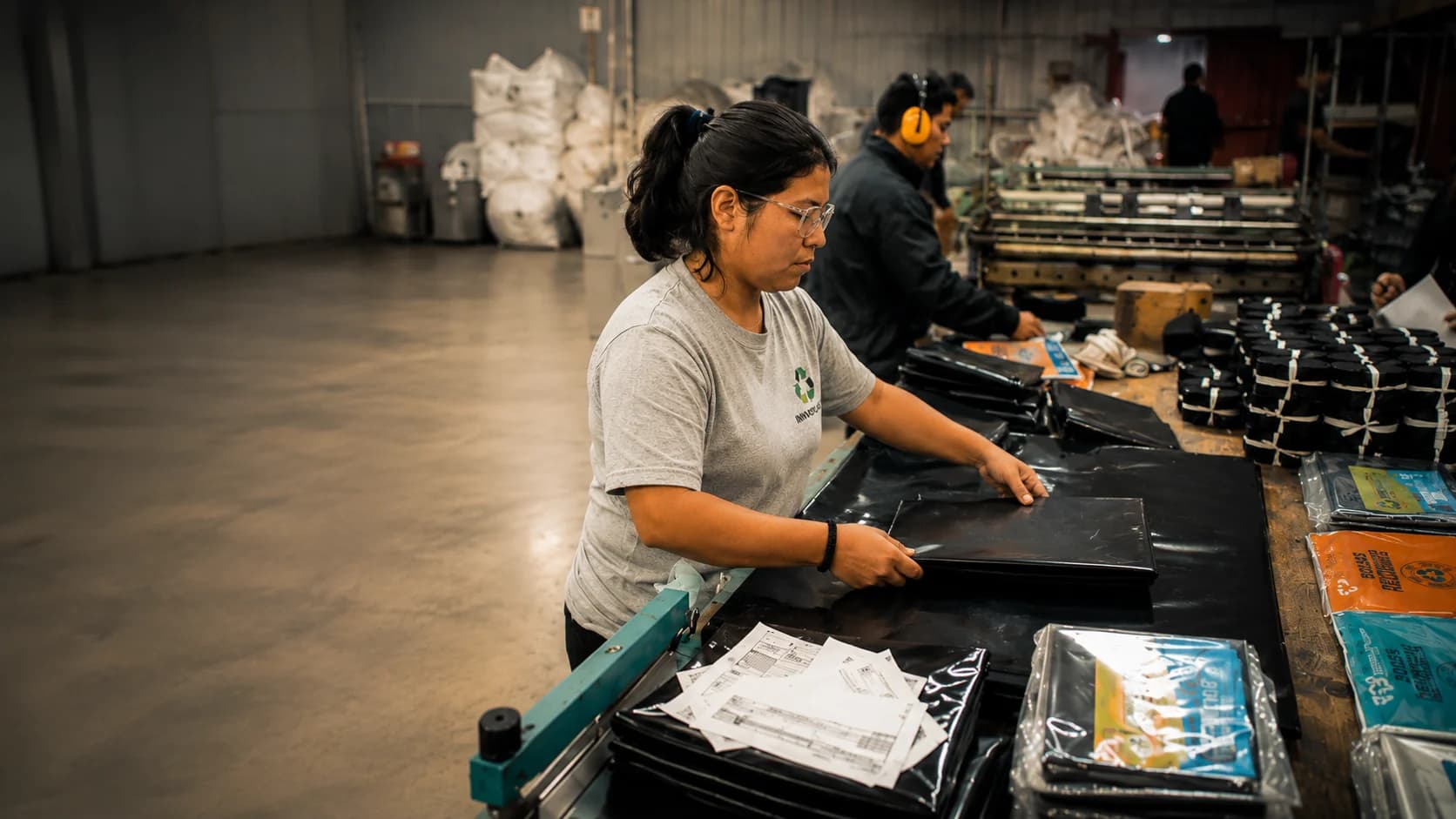 Trabajadora boliviana empacando láminas recicladas en la planta de su empresa
