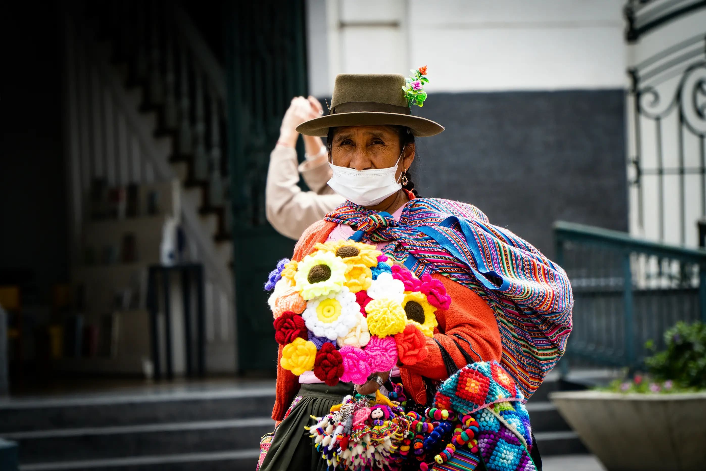 Mujer mayor andina vendiendo flores tejidas a crochet en una plaza de Bolivia